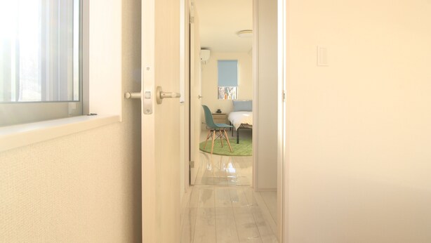 A hallway leading to a bedroom with a bed, a chair, and a small table.