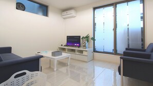 A modern living room with a flat-screen TV, a coffee table, and two sofas.