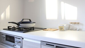 A kitchen with a stove, a kettle, and some jars on the counter.