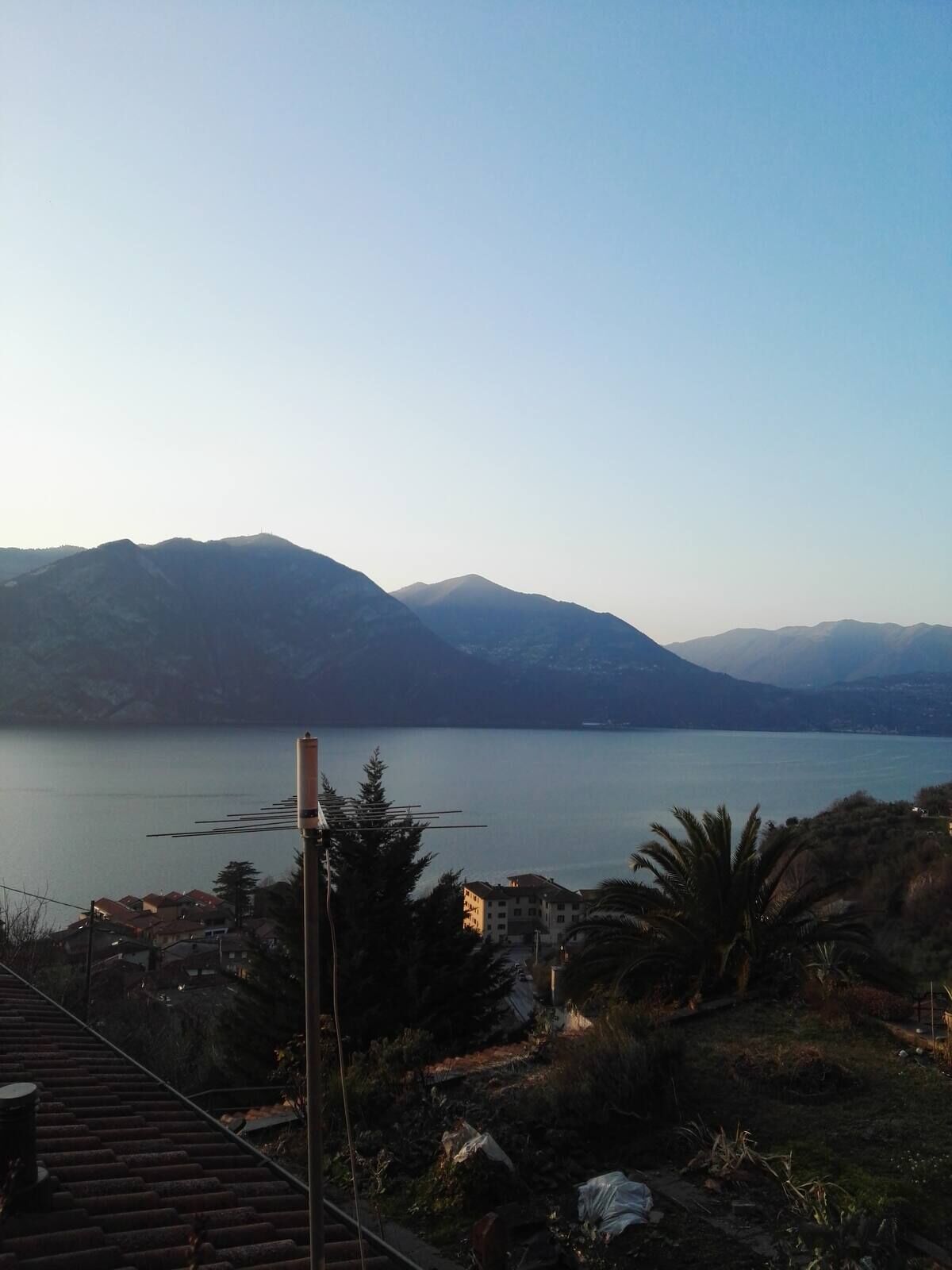 A view of a lake with mountains in the background and a residential area in the foreground.