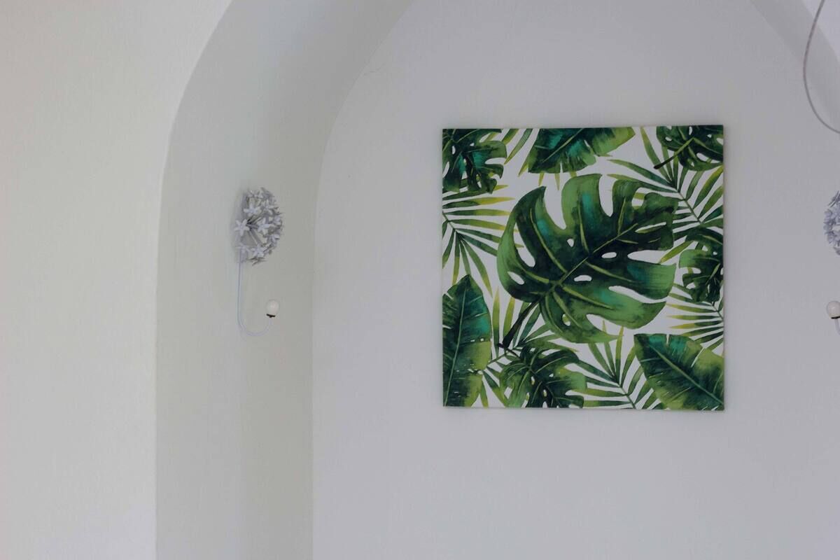 Een kamer met een groot kunstwerk op de muur met een tropisch bladmotief.