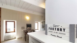 A spacious kitchen with a white countertop, a vintage 'Retro Factory' sign, and a dining area with a table and chairs. - LOVELY APARTMENT IN AN ANCIENT HAMLET WITH LAKE VIEW AND PATIO (Marone)