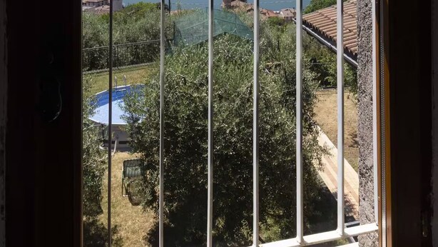 A window with a view of a lake, mountains, and a small building. - LOVELY APARTMENT IN AN ANCIENT HAMLET WITH LAKE VIEW AND PATIO (Marone)
