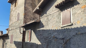 A stone building with a central arched doorway, a staircase leading to an upper level, and a small window with shutters. - LOVELY APARTMENT IN AN ANCIENT HAMLET WITH LAKE VIEW AND PATIO (Marone)