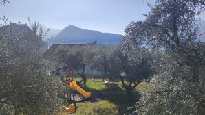 A playground with a slide and climbing structure, surrounded by olive trees and a mountain in the background. - LOVELY APARTMENT IN AN ANCIENT HAMLET WITH LAKE VIEW AND PATIO (Marone)
