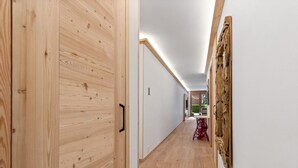 A hallway with wooden flooring and walls, a wooden door, and a red chair.