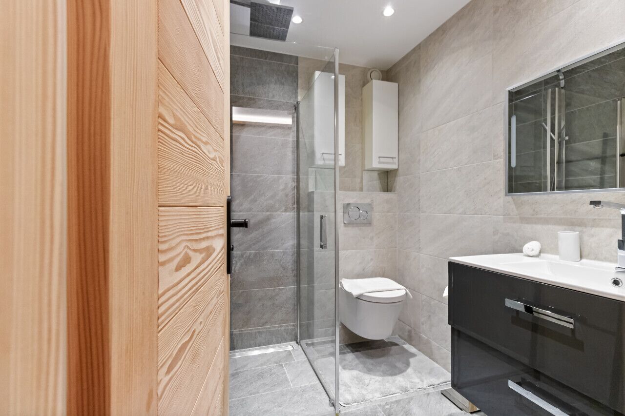 Une salle de bain moderne avec une douche à parois de verre, des toilettes et un meuble-lavabo avec un miroir.
