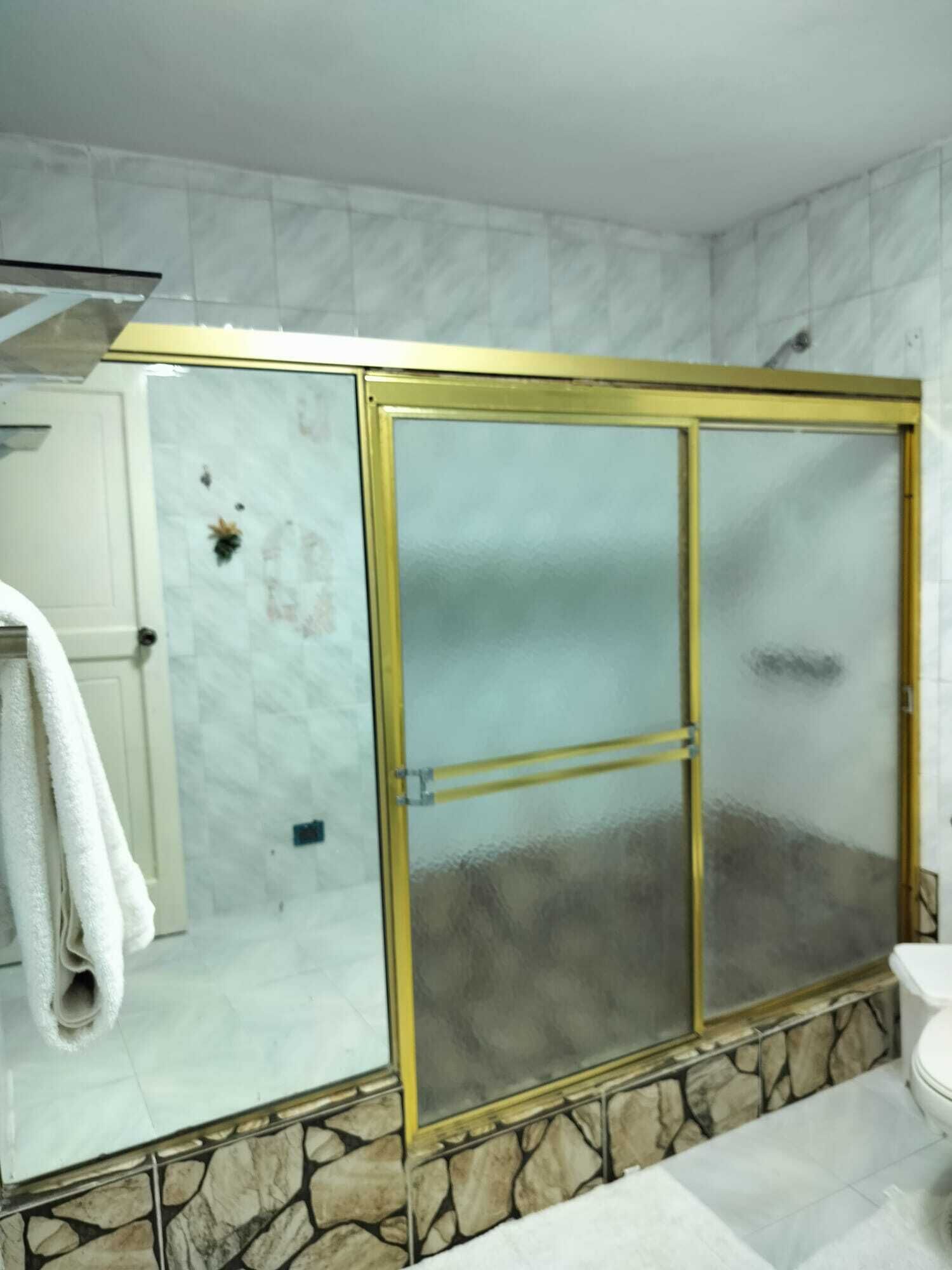 Une salle de bain avec une douche à parois de verre, des éléments décoratifs en pierre et une serviette blanche accrochée au mur.