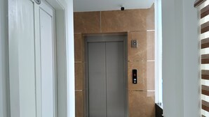 Um elevador com mostrador digital, painel de comandos e porta identificada como "G3".