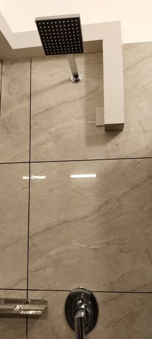 A bathroom with a shower head, a faucet, and tiled walls. - Paul residency (Aluva)
