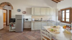 A compact kitchen with white cabinets, a built-in microwave, and a small dining area with a table set for two. - Bellavista at Podere il Moro (Toscana)