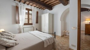 Ein Schlafzimmer mit einem Bett, einem Kleiderschrank, einem Heizkörper und einem Fenster mit Vorhängen.
