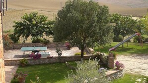 Ein Garten mit Tischtennisplatte, Rutsche und einer Pergola.