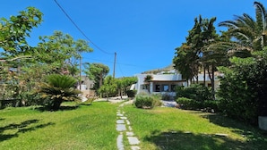 A well-maintained garden with a stone pathway leading to a white building with a balcony.
