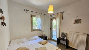 A bedroom with a bed, a bedside table, a lamp, a radiator, and a window with curtains.
