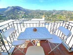 Un balcon avec une table et deux chaises, donnant sur un paysage montagneux.