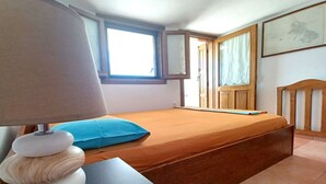 Ett sovrum med en säng, ett skrivbord med en lampa, ett fönster och en dörr.