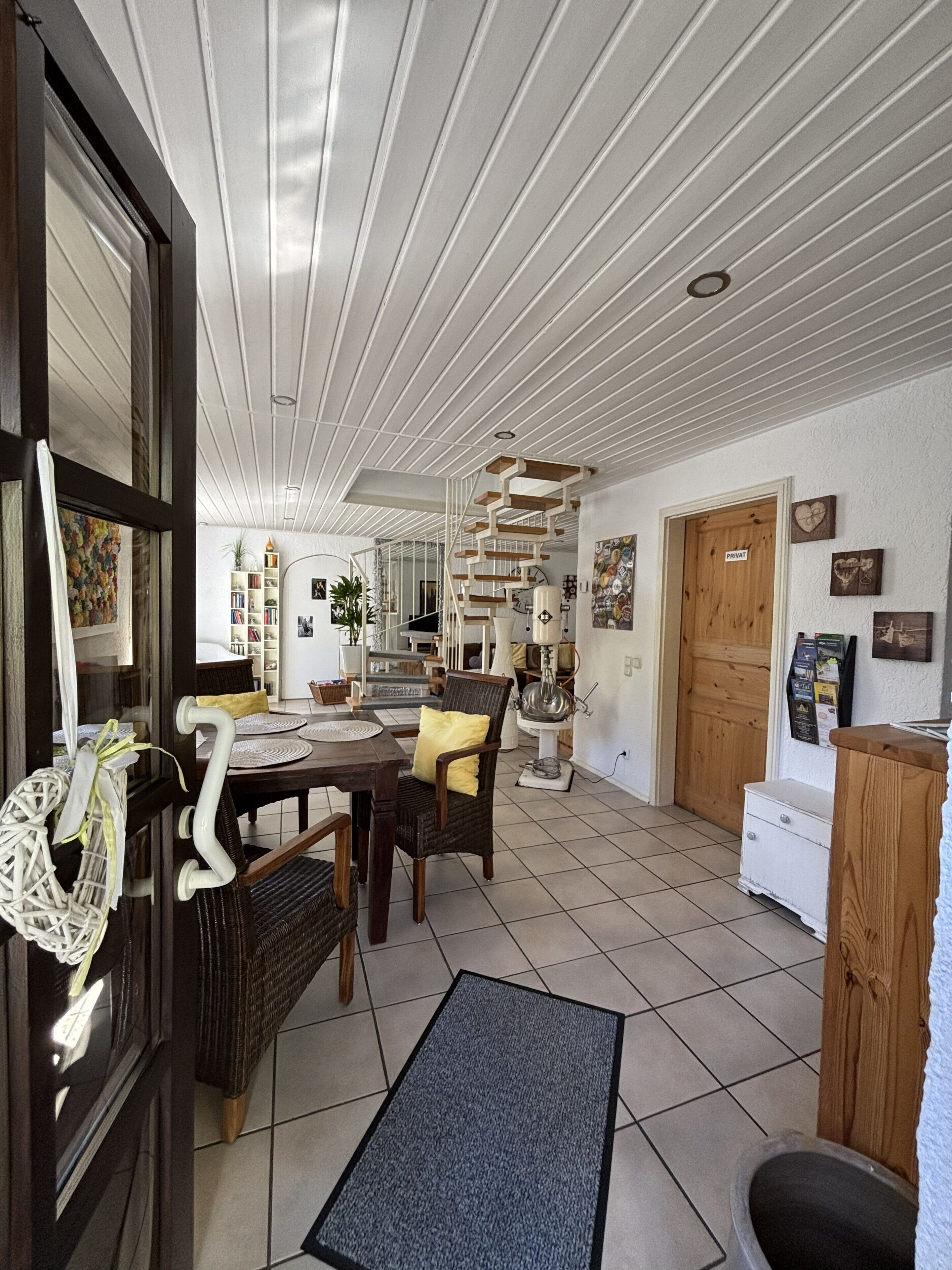 Une pièce spacieuse comprenant un coin repas, un escalier et une porte privative.