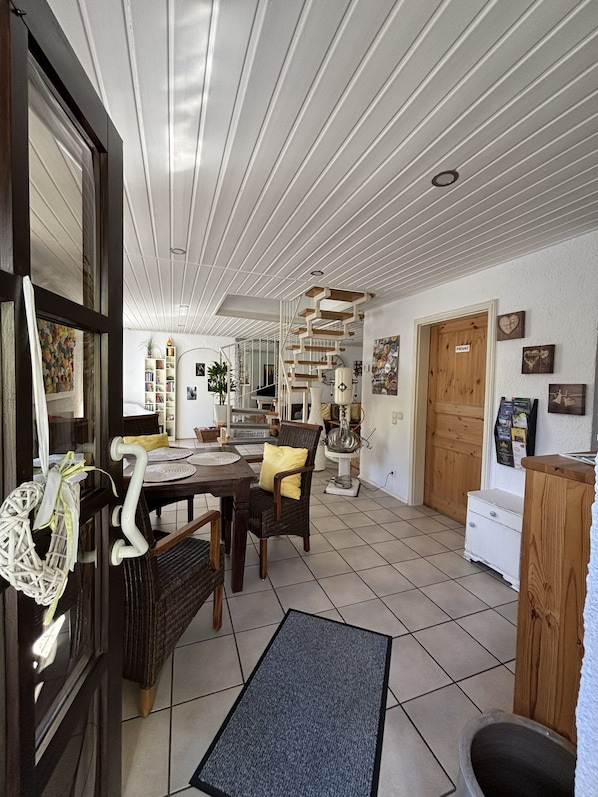 Una habitación amplia con comedor, una escalera y puerta privada.