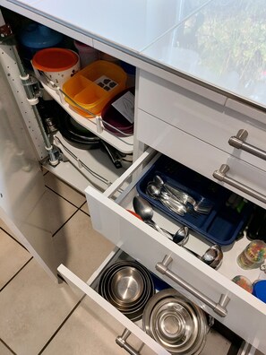 A kitchen with white cabinets, a blue tray with utensils, and a red container.
