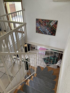 A staircase with a white railing, a colorful wall decoration, and a small table with a pink tablecloth.