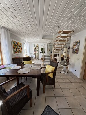 A spacious dining area with a high ceiling and a staircase leading to an upper level.