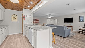 Una cocina moderna con armarios blancos, encimera de granito y techo de madera.