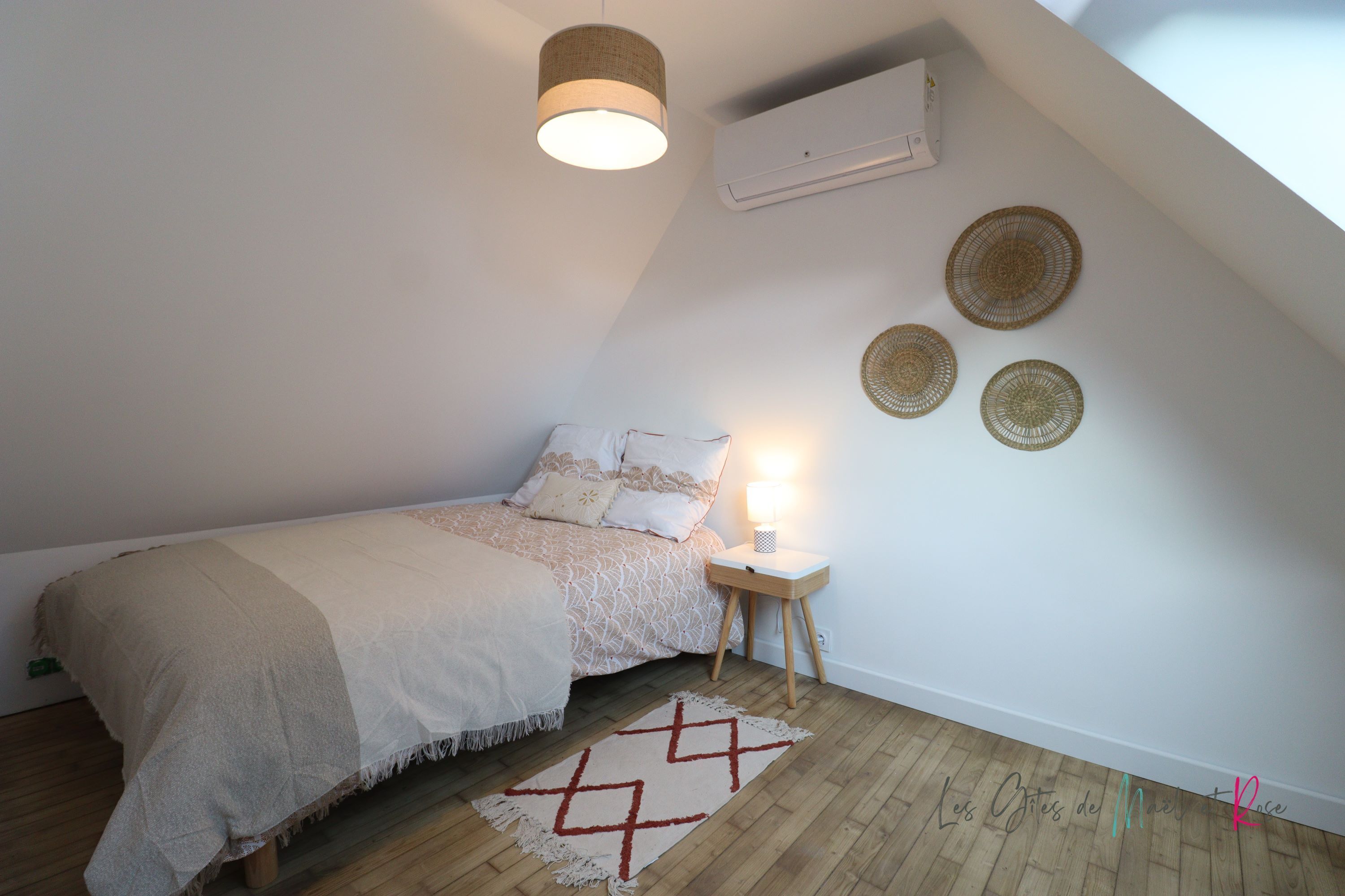 Un dormitorio con cama, lámpara de noche y adornos en la pared.