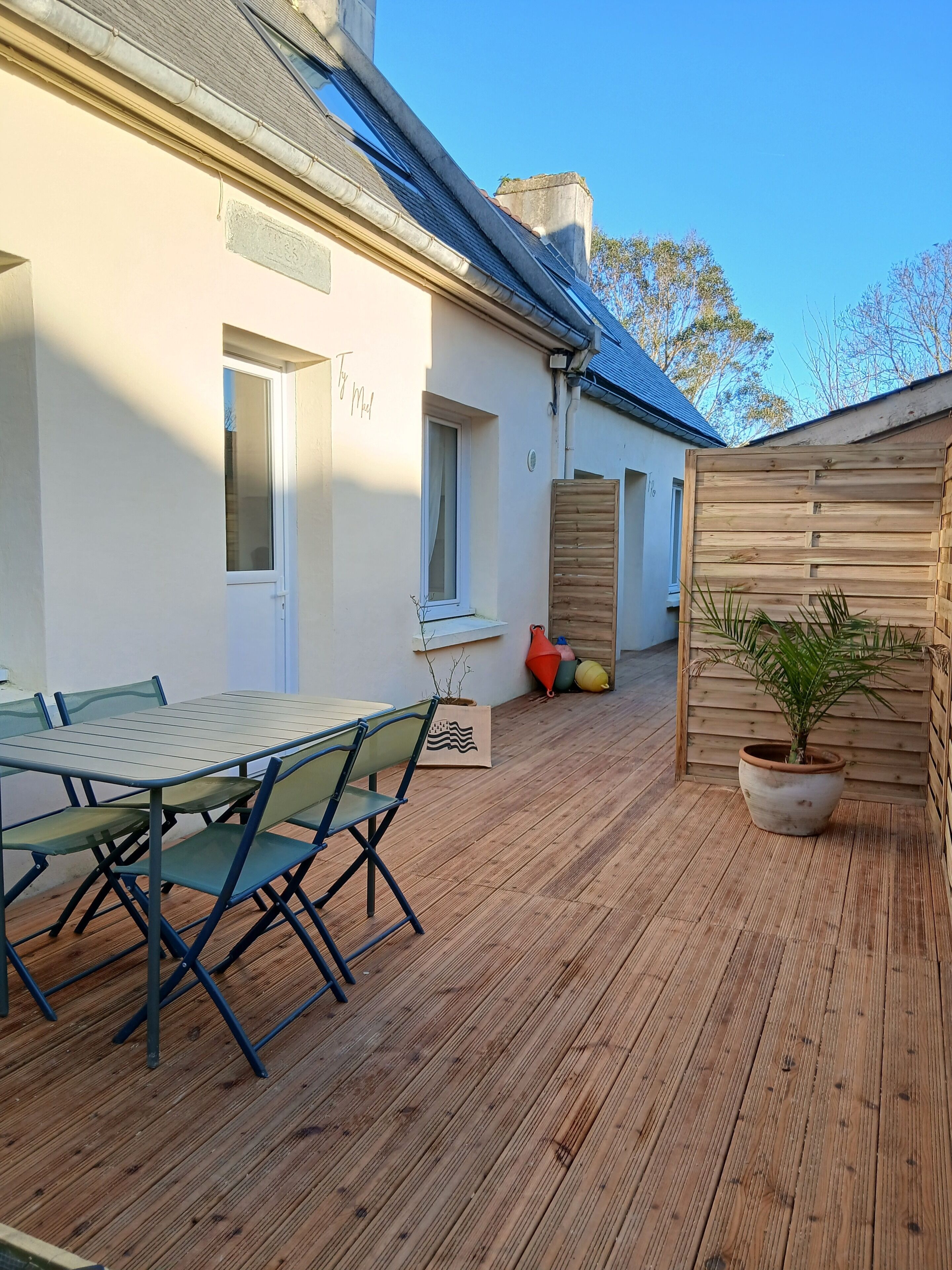 En træterrasse med et bord og stole, en plantekasse og et træhegn.