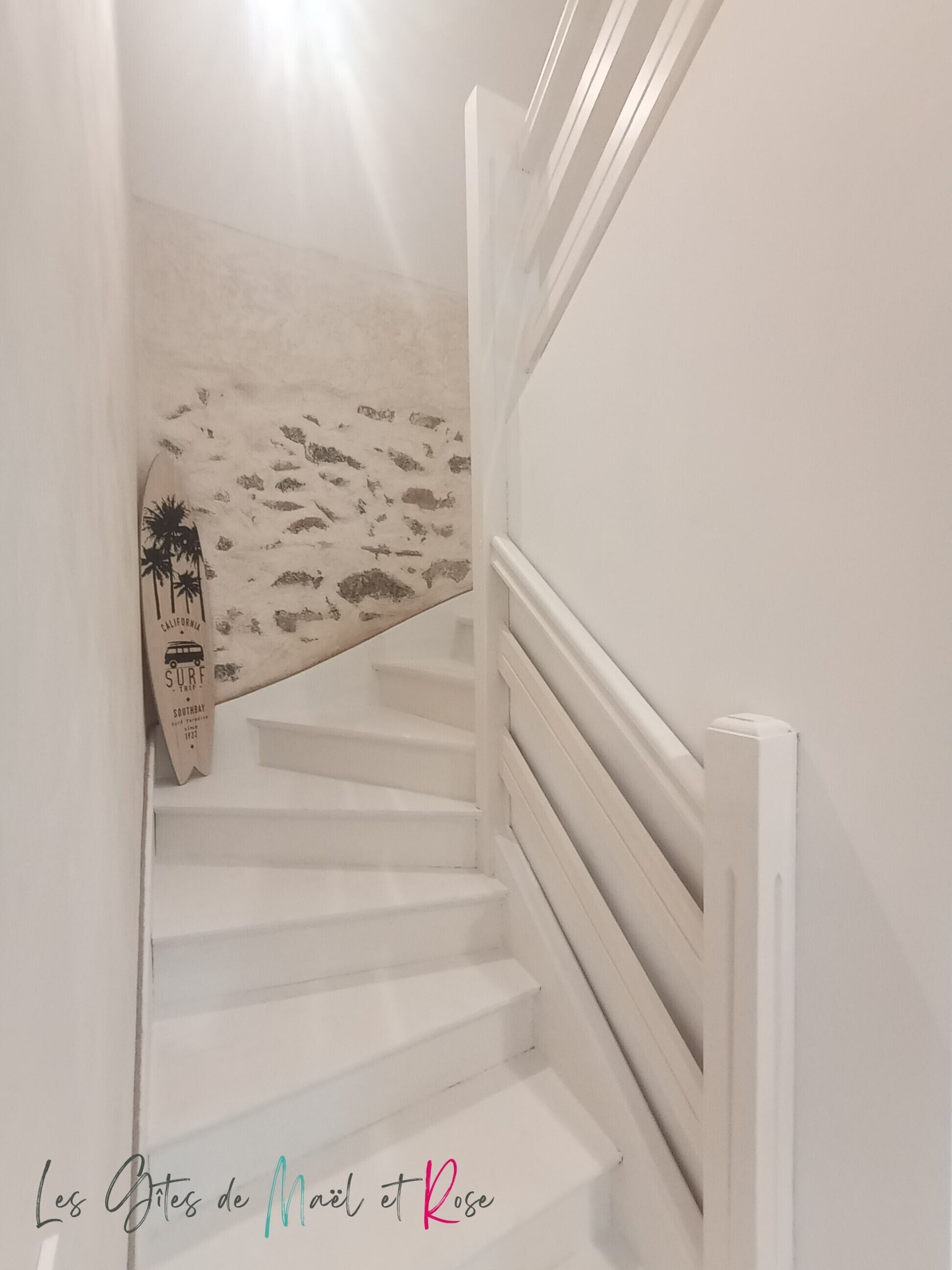 A white staircase with a surfboard decoration and a palm tree sign.