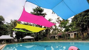 A swimming pool with inflatable toys, a blue shade sail, and a white tent in the background. - The Beach Park hadsan by Hiverooms (Lapu-Lapu)