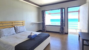 A bedroom with a bed, a table, and a view of the beach. - The Beach Park hadsan by Hiverooms (Lapu-Lapu)