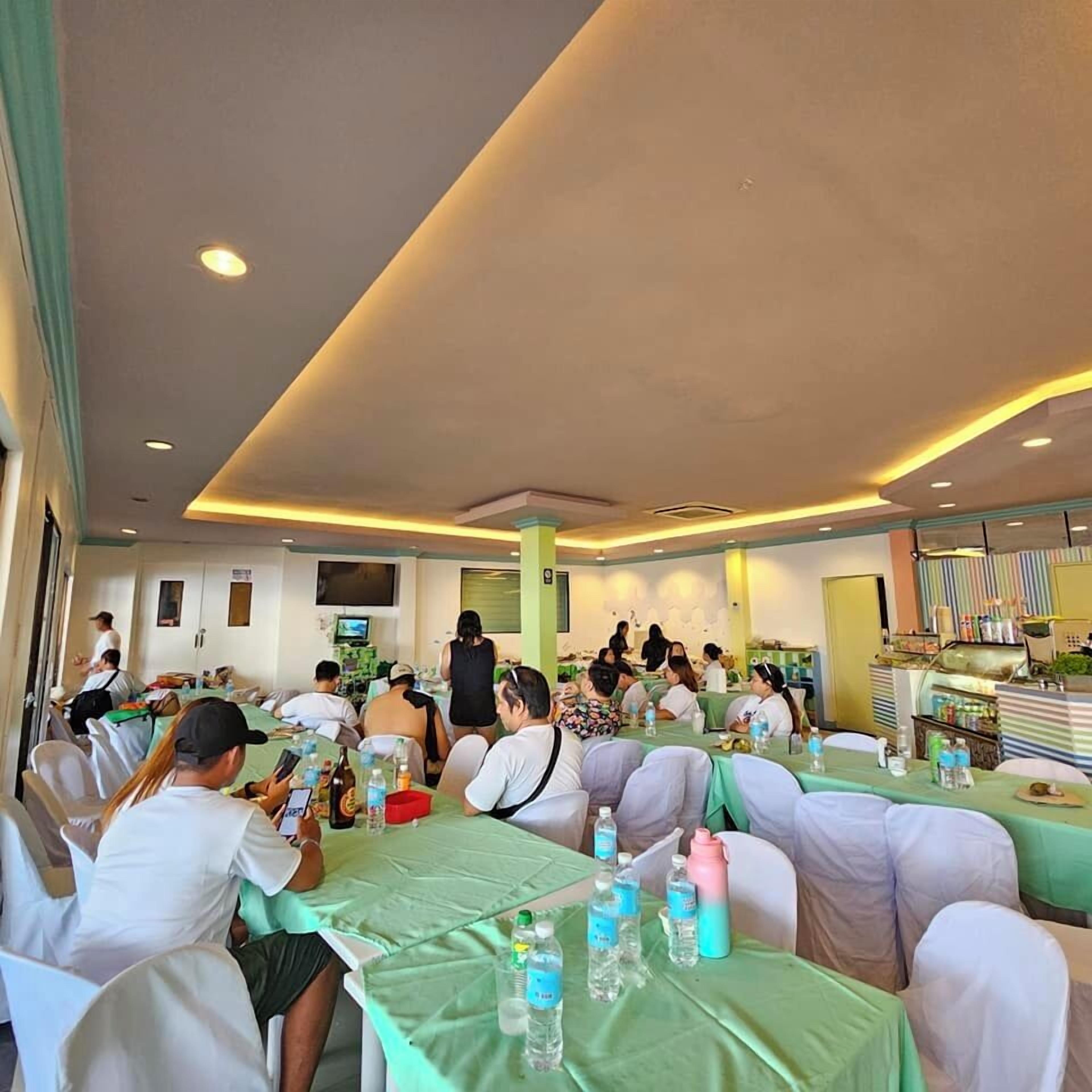 Un comedor con mesas cubiertas de manteles verdes, sillas y botellas de agua.