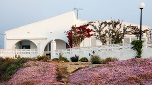 Un edificio blanco con arcos, una cerca blanca y un farol.