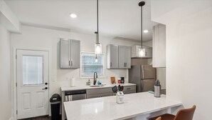 Una cucina moderna con isola centrale, elettrodomestici in acciaio inossidabile e illuminazione a sospensione.