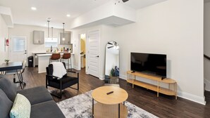 A modern living room with a sofa, coffee table, TV stand, and ceiling fan.