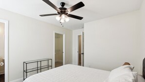 A bedroom with a bed, a ceiling fan, and a nightstand.