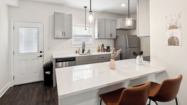 A modern kitchen with white cabinetry, a white countertop, and a central island with seating.
