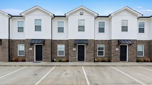 A row of townhouses with brick facades and white trim, numbered L2 to L4, and a parking lot in front.
