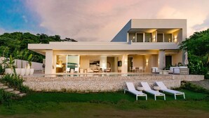 Una casa moderna de dos pisos con piscina, mobiliario exterior y un jardín bien cuidado.
