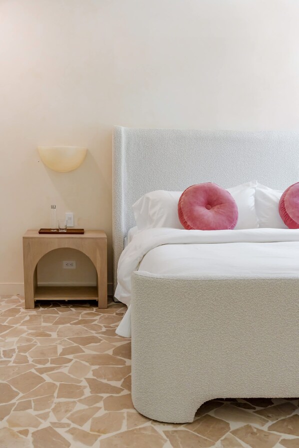 A neatly arranged hotel room with a bed, a bedside table with a lamp, and a small wooden cabinet.