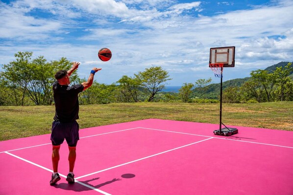 A person playing basketball on a pink outdoor court with a basketball hoop.