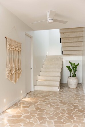 A staircase with a modern design, a ceiling fan, and a potted plant.