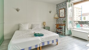 Un dormitorio con cama, mesita de noche, silla, ventana y radiador.