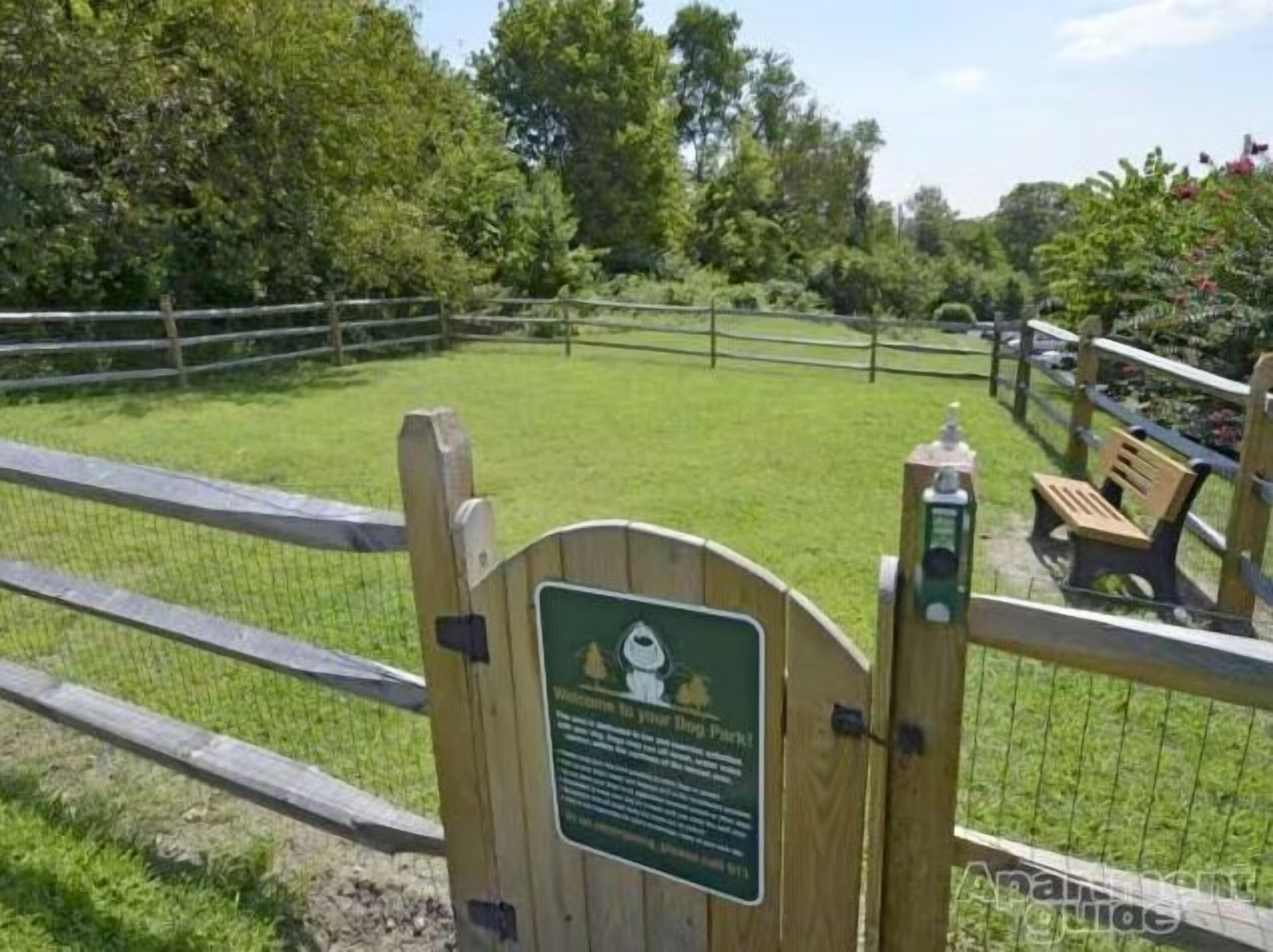 Un portal de fusta amb un cartell que dona la benvinguda als visitants a un parc de gossos.