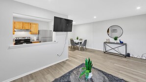 Una cocina moderna con armarios de madera, horno empotrado y televisor de pantalla plana.