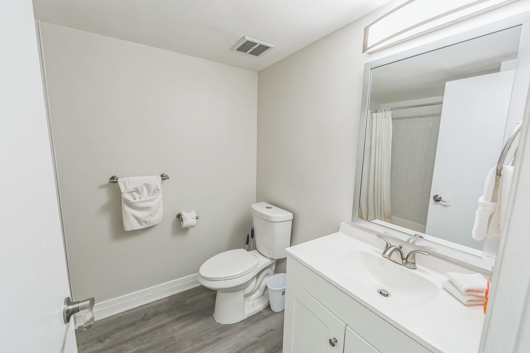 A modern bathroom with a toilet, sink, and mirror.