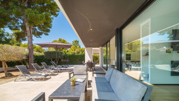 An outdoor patio area with lounge chairs, a sofa, and a table, featuring a glass wall and a view of the surrounding landscape. - V. Ca Na Rosa With Private Pool (Mal Pas - Bon Aire)