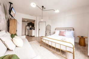 Ein Schlafzimmer mit Bett, Nachttisch und einem an der Wand montierten Fernseher.
