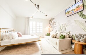 Ein Schlafzimmer mit einem Bett, einem Sofa, einem Fernseher und einer Pflanze.